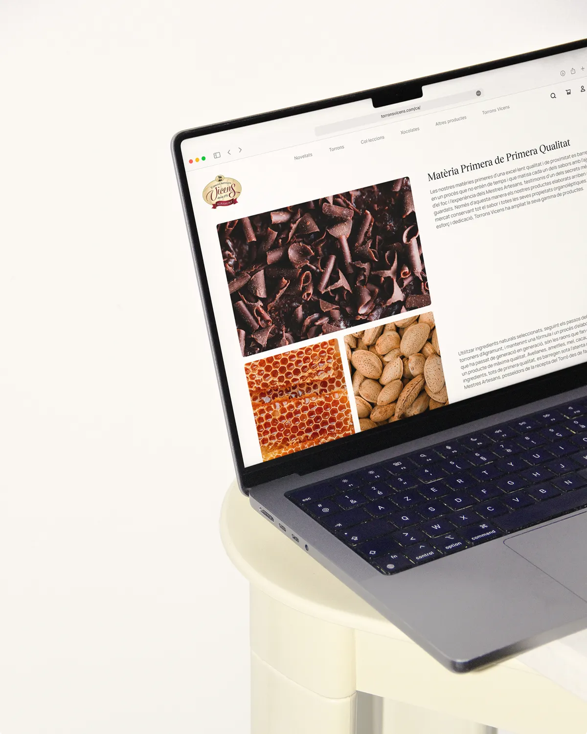 Image of a MacBook laptop sitting on a white table displaying a page of the Torrons Vicens website, which shows information about the nougat's composition.